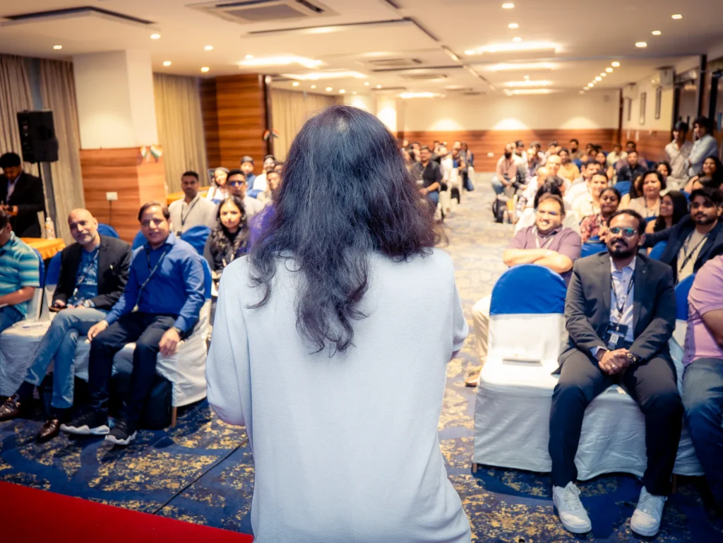 Audience member asking a question during a corporate conference while the speaker listens.