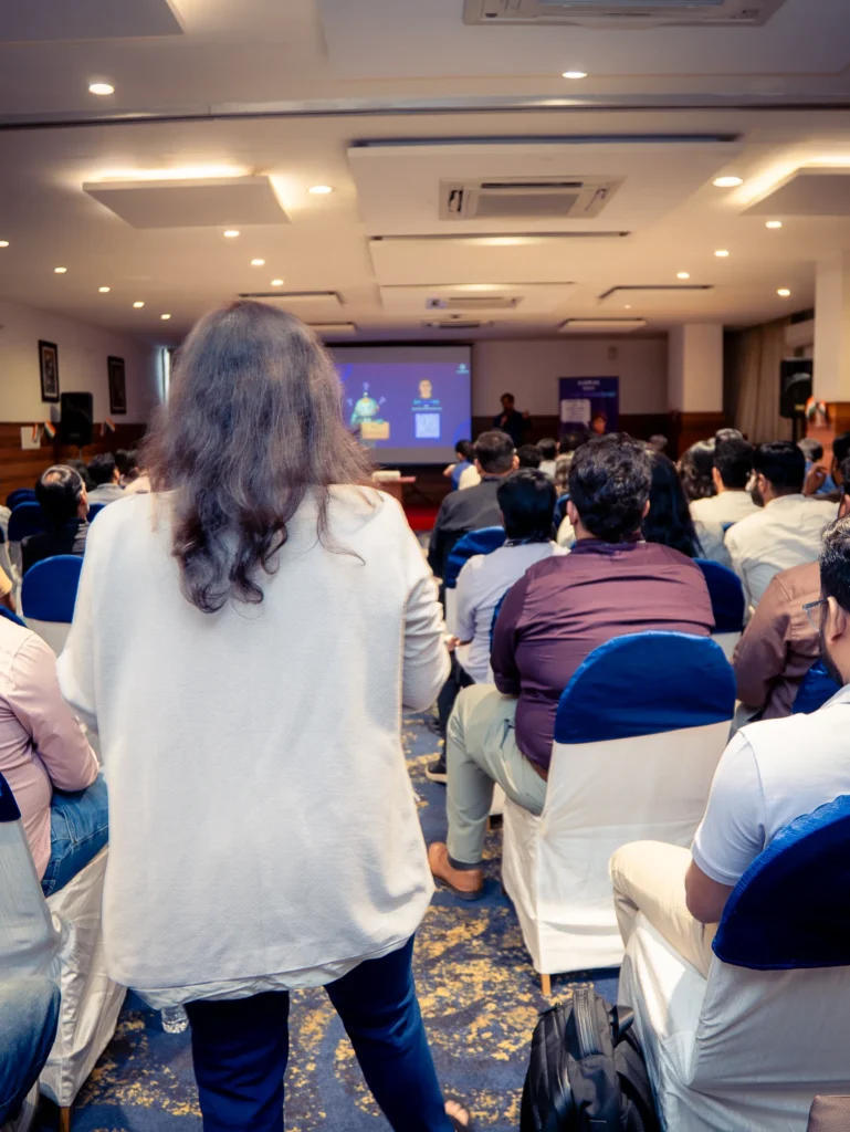Speaker presenting on stage during a corporate workshop while interacting with attendees.
